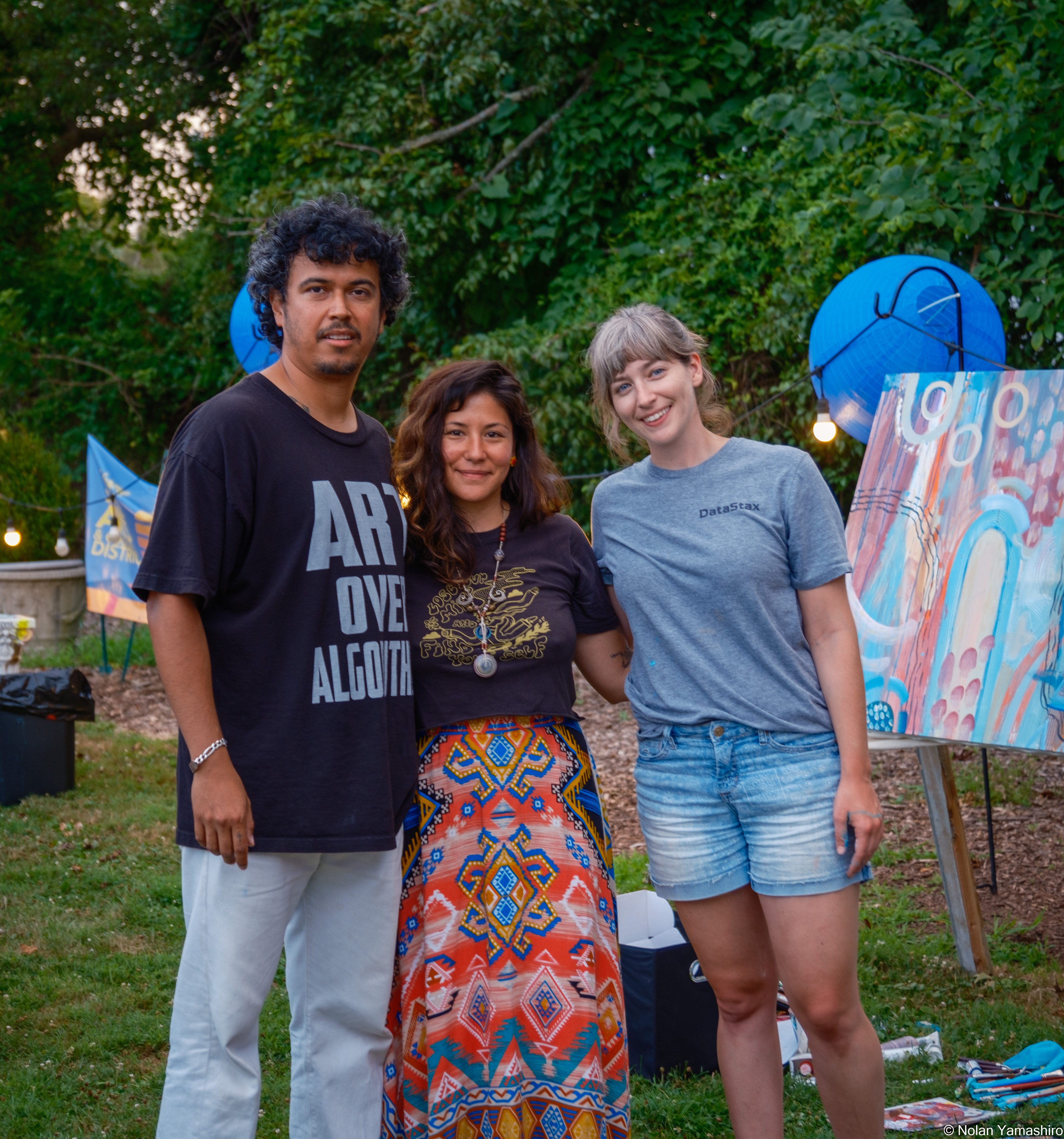 Mural Battle organizer and two artists standing in grass outside of DIY